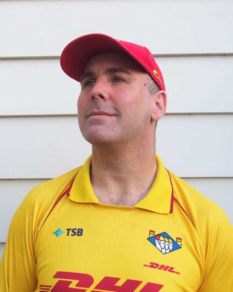1. Male surf lifesaver in yellow uniform and red cap at Raglan Beach, New Zealand, promoting safety and rescue services.